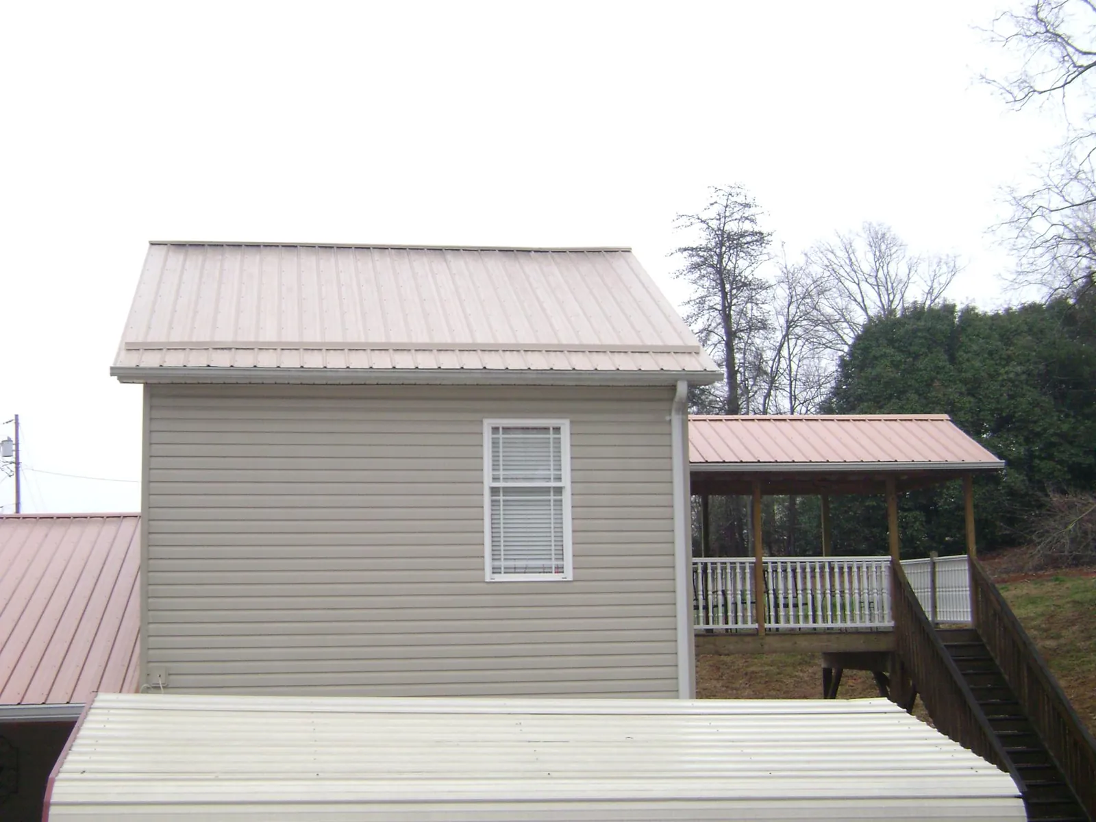 Tan metal roofs on a two story addition and attached porch, from a Roof Replacement job in Lakeville